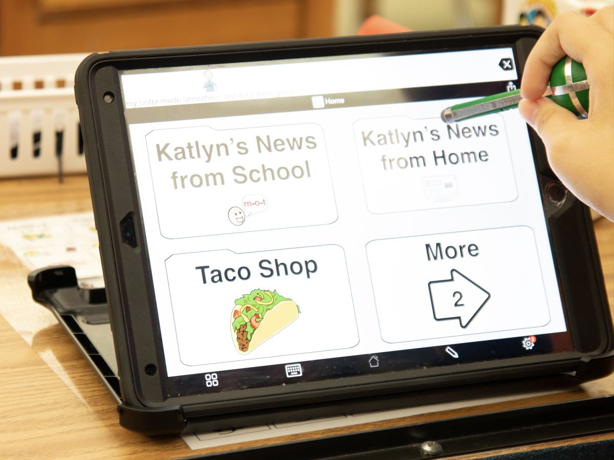 Katlyn selects programmed speech options on her iPad, using the optimized software and her new stylus.