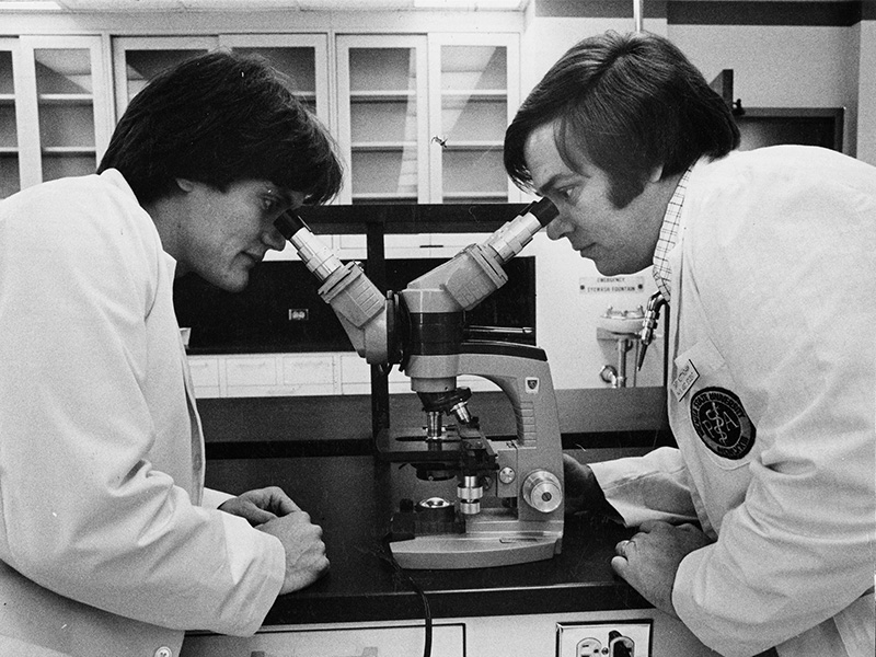 Physician Assistant students look through a microscope in 1977