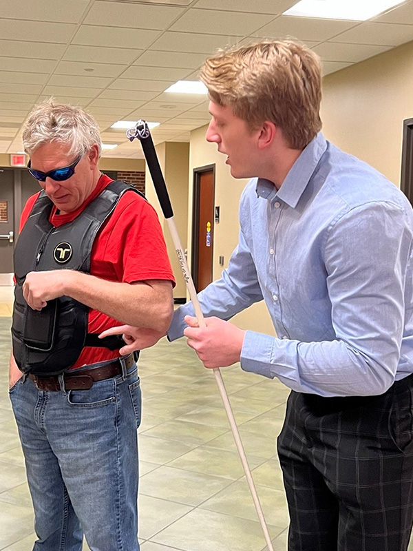 Grant Johnson testing a prototype of Vision Vest with the aid of blind individual