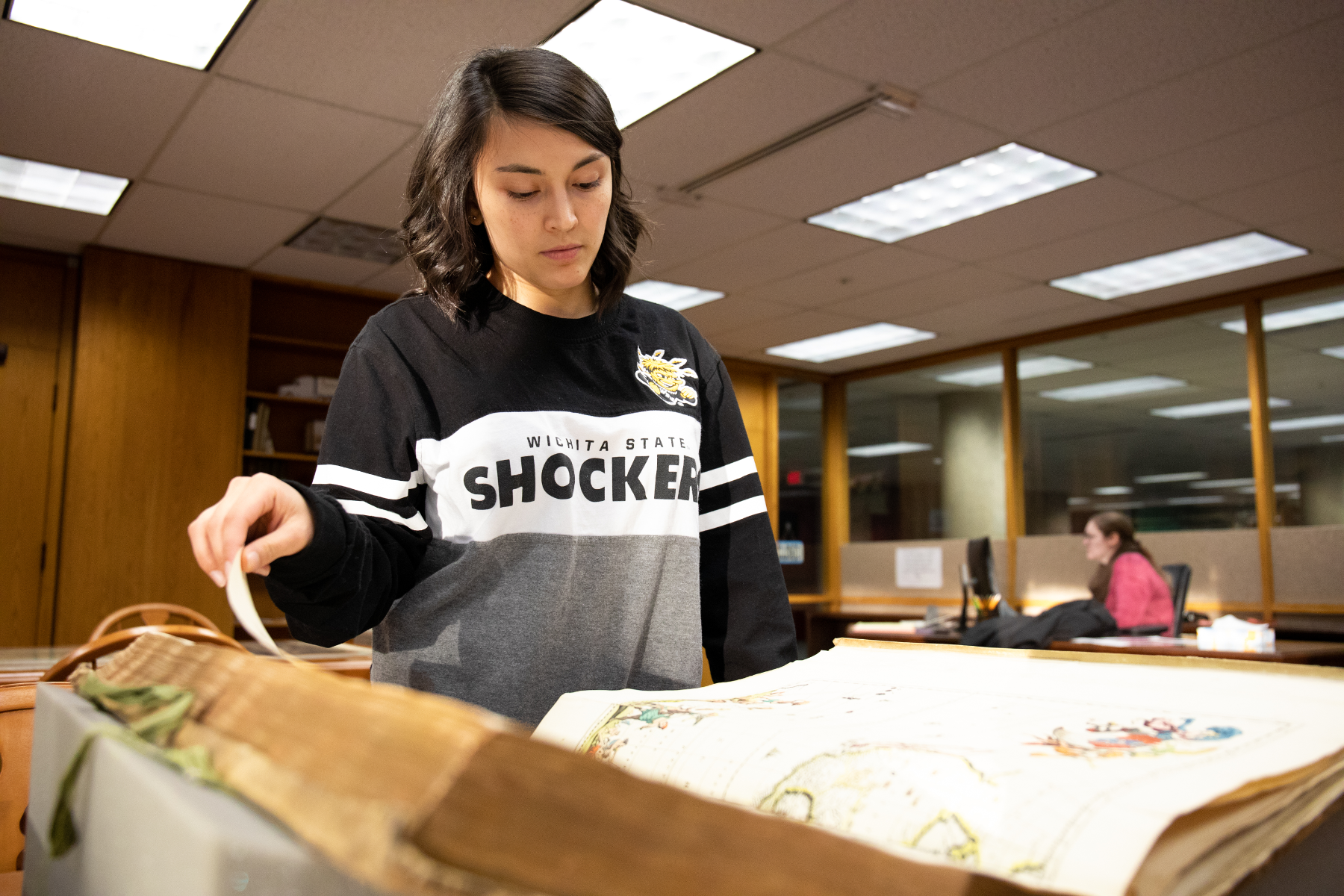 student examining rare book in the archives