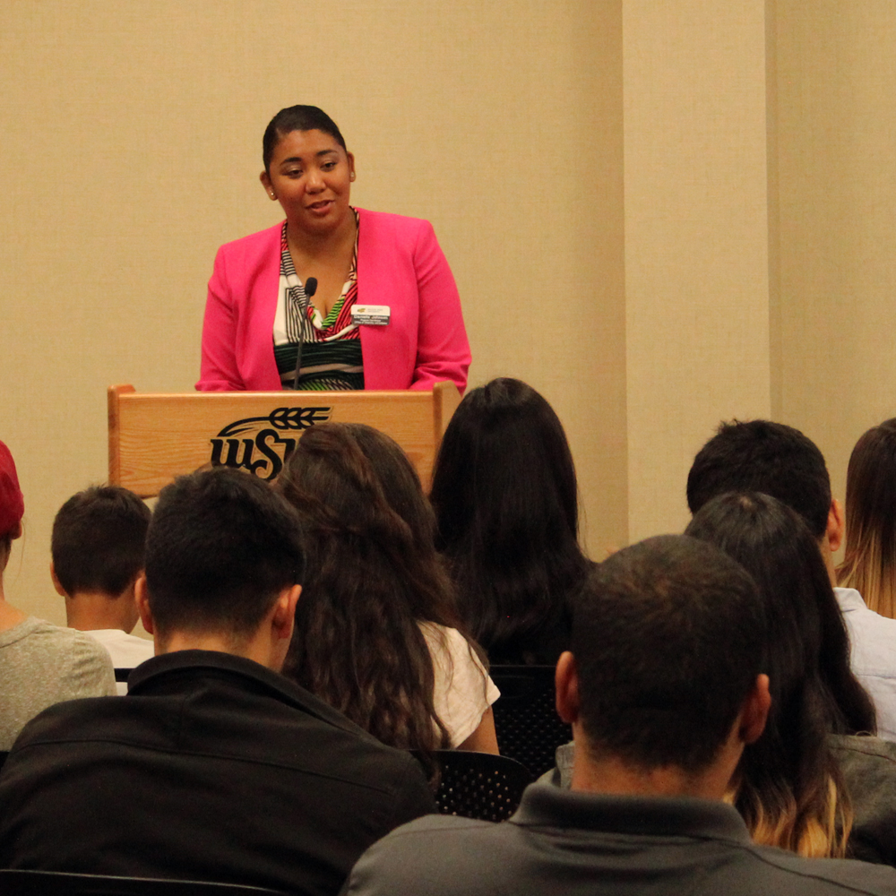 An employee speaking at the podium to a group at a diversity training.