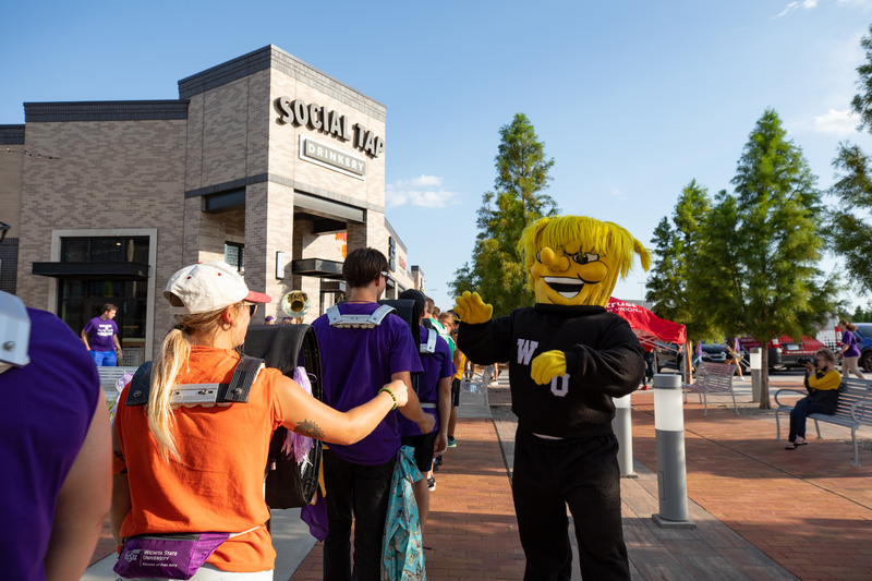 Photo of Wu high fiving a student in band