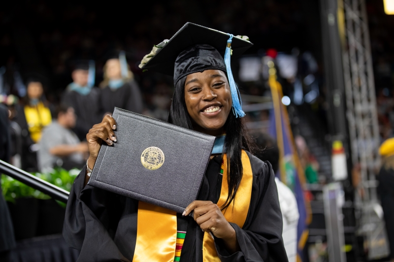 Female POC graduate holding diploma cover