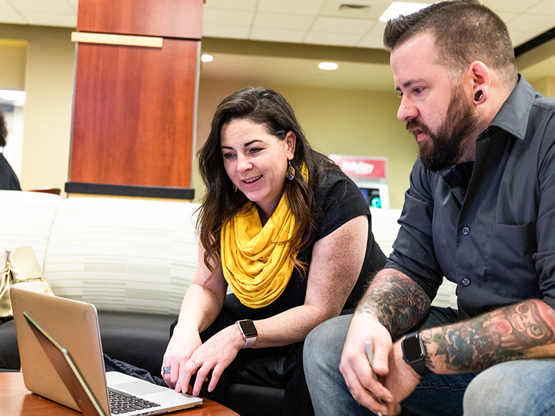 Two adult learners working together on a laptop