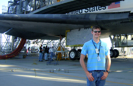 Peter Fast stands in front of a NASA spacecraft at the Dryden Flight Research Center in California.