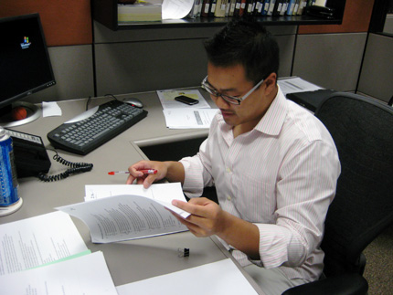 Hoainam Duong grades papers at his desk in the Center for Entrepreneurship. He is a graduate assistant for Jim Wolff.