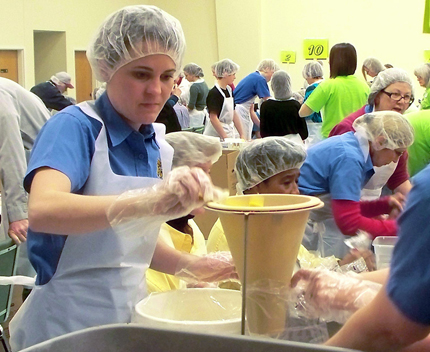 A WSU staff member pours ingredients into a funnel during the Feed Haiti event at the WSU Metropolitan Complex.