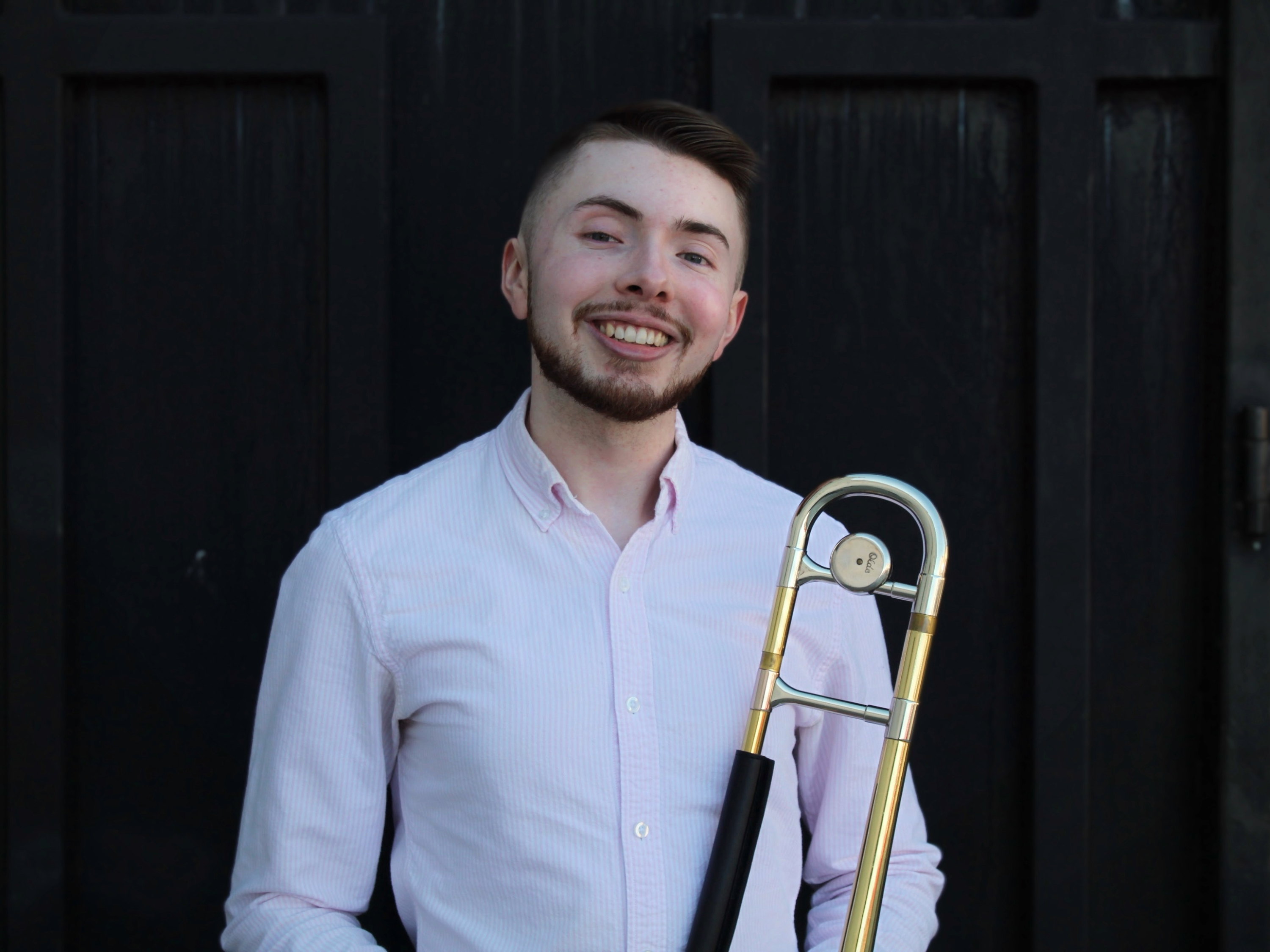 Graduate student Doug Ragon holding his trombone