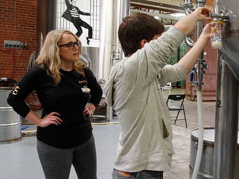 As a new intern at a local brewery, Wichita State student Alex Zeorlin is learning the finer points of lab testing beer from fellow student Alexandrea Feldkamp, WSU's first intern at Wichita Brewing Co.