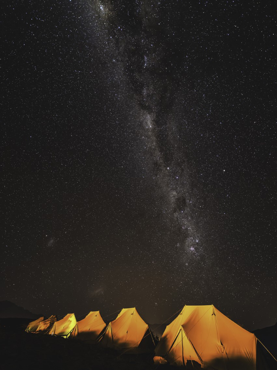 Martin's campsite tents on the mountains of Chile stand illuminated against a vividly dark sky.