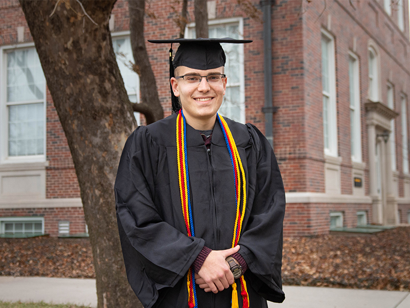 Andrew Martin poses in his regalia in front of Morrison Hall