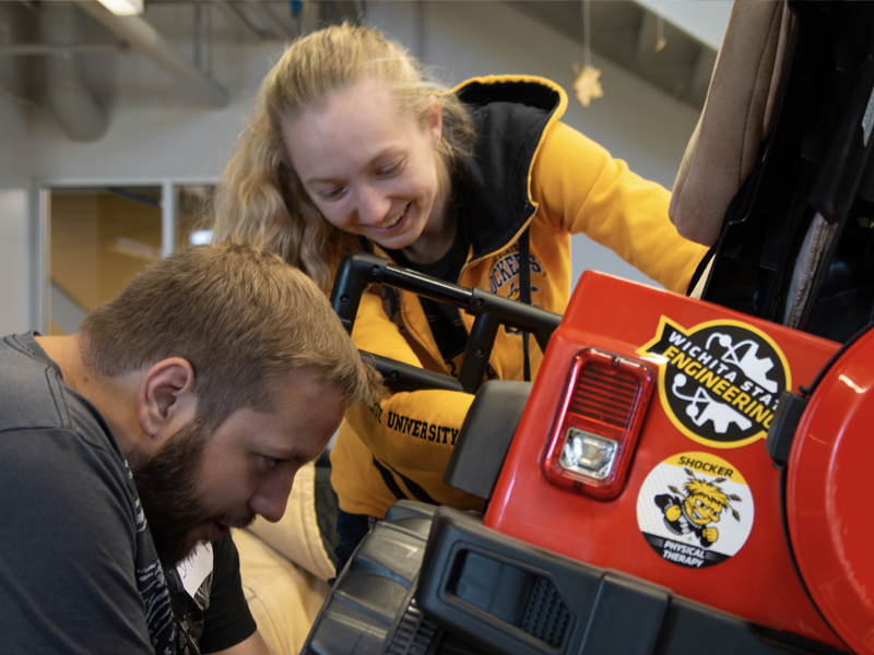 Engineering students work on a child's car under the GoBabyGo program