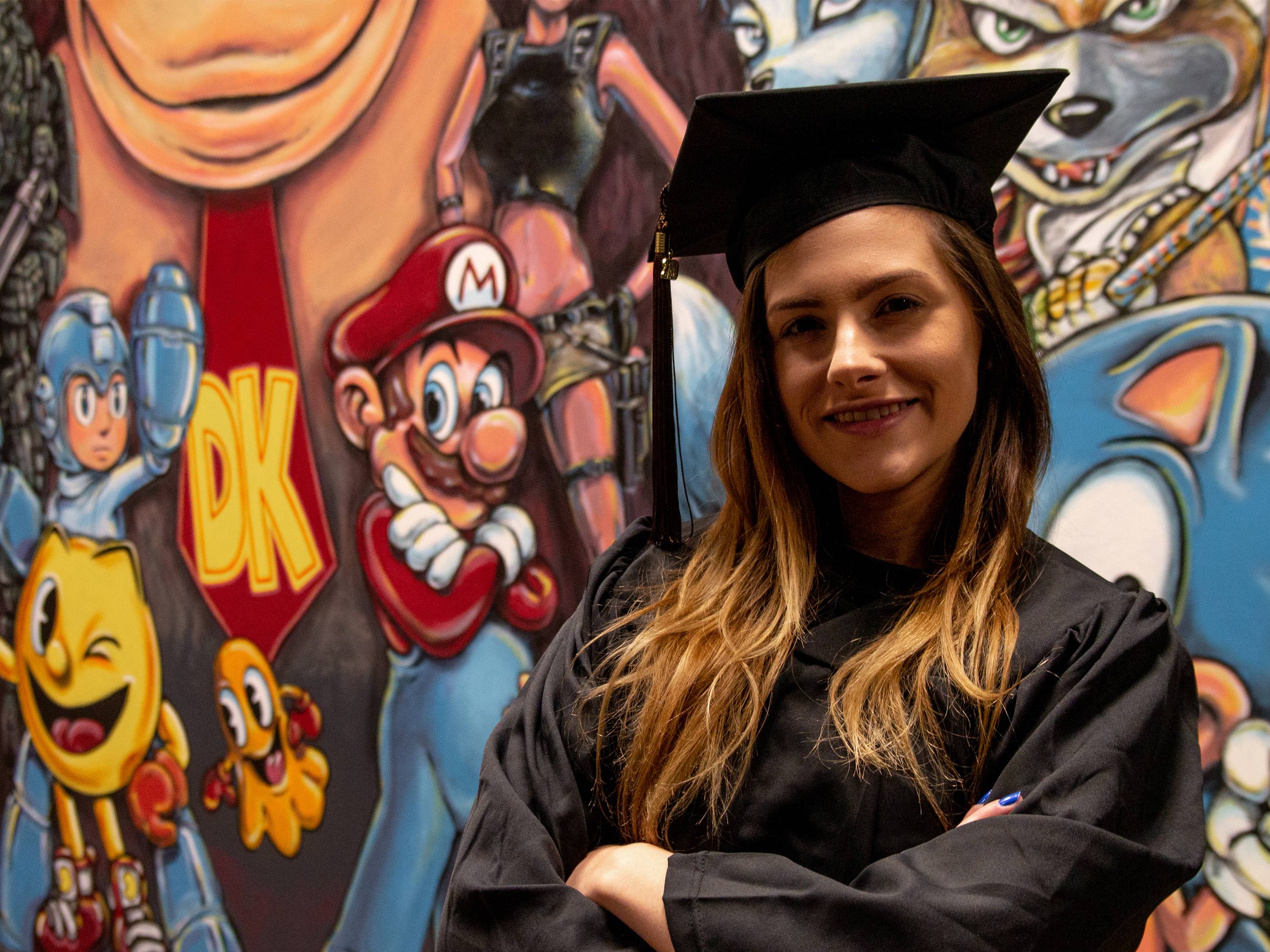 Michaela Marioni poses in front of a Nintendo character mural at Shocker Studios