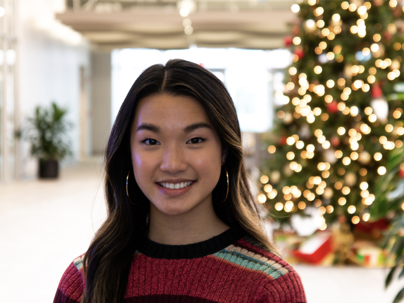 Stella Yang, economics grad, standing near the Christmas foliage in the Airbus lobby