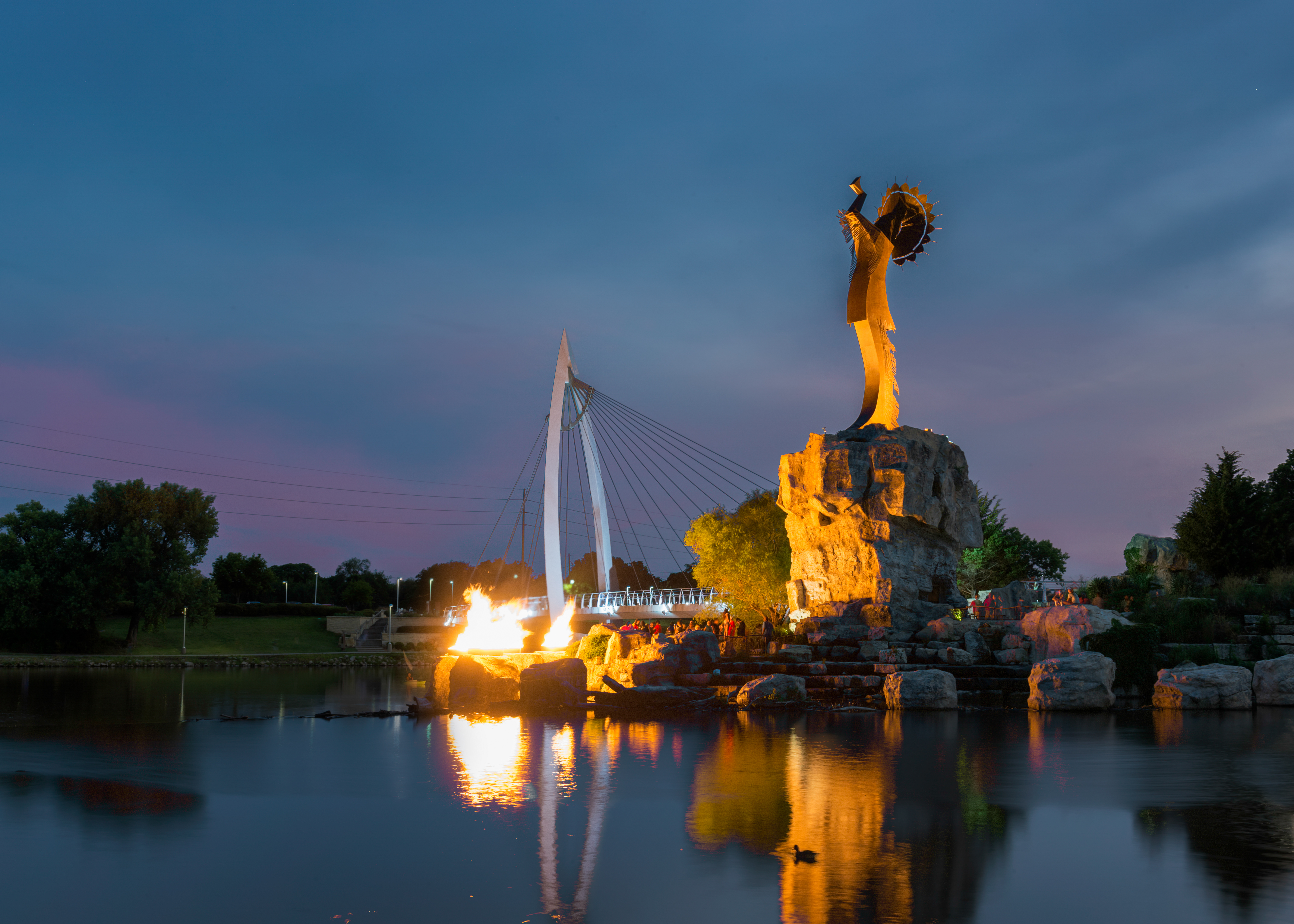 The Keeper of the Plains lit by fire at dusk