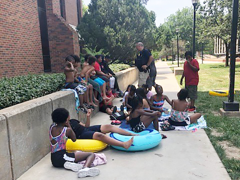 Member of Wichita State police department play dodge ball with children from local community.