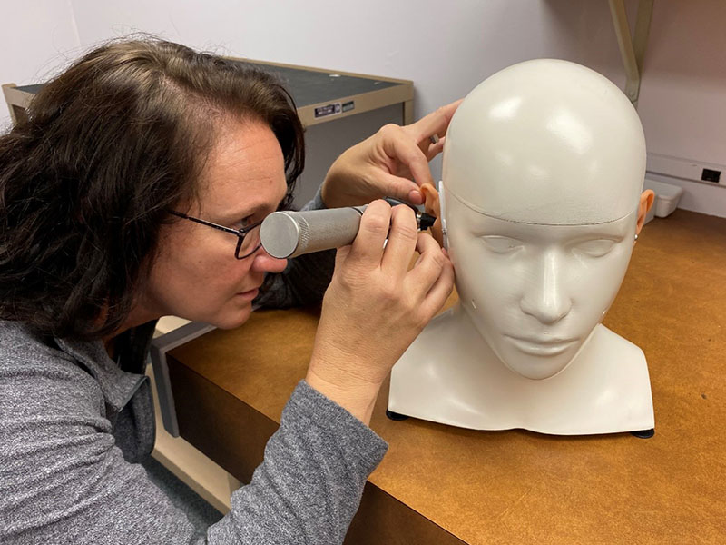 audiology student examines simulation manikin