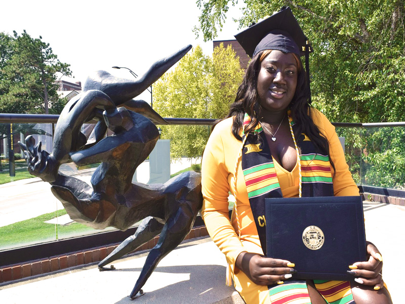 Aunjnae White, a first-generation student, posing with her degree in psychology.