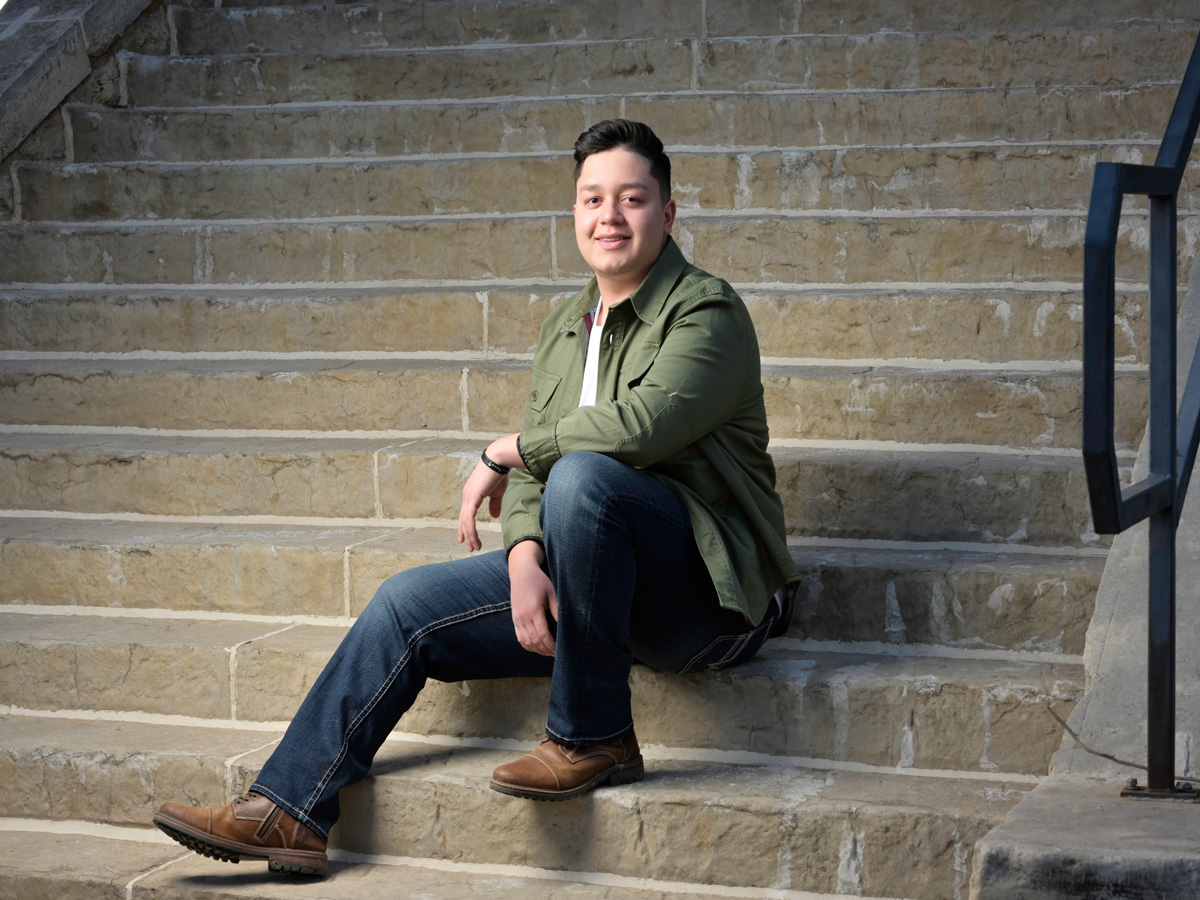 Pedro Piña-Guerrero is sitting on some long limestone steps with his hands crossed and a smile on his face.