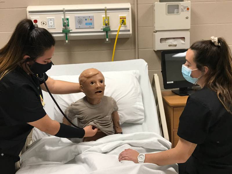 nursing students work with simulation manikin