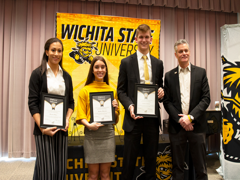 Three winners of Wichita State's Gore scholarship, Caden Carlson, Brynna Mays, and Audrey Muma stand with Dr. Rick Muma, president of WSU..