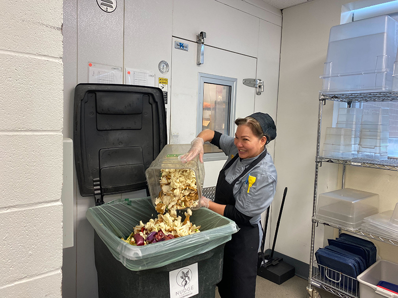 A member of the kitchen crew dumps food scraps into a bin at Shocker Hall.