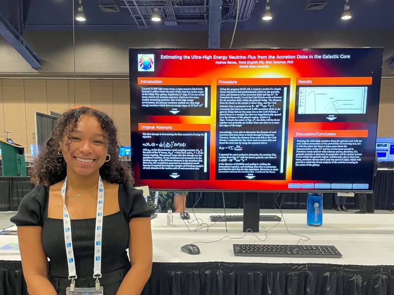 Ayshea stands in front of her research poster.