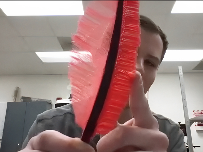 Will Johnston holds up a 3D printed owl feather prototype.