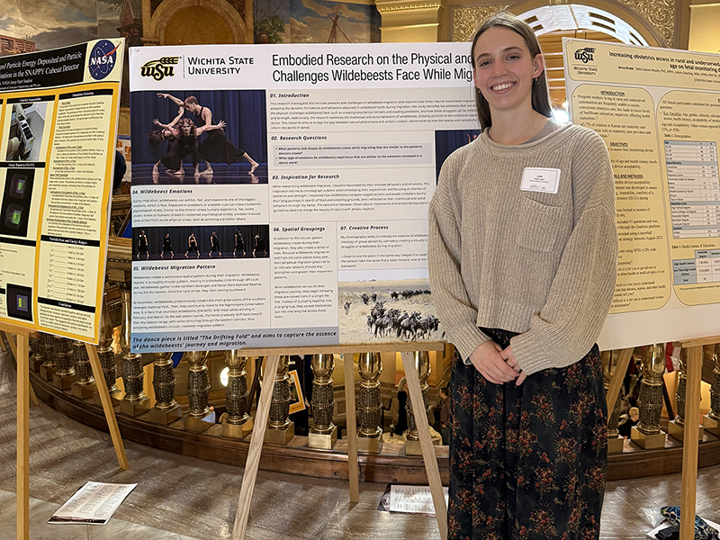 Lille Nightingale poses in front of her research poster at the Kansas state capitol 