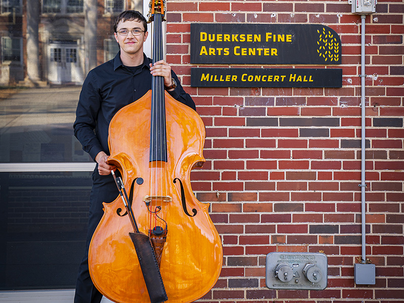 John Mark Koontz poses with his double bass outside Duerksen Fine Arts Center