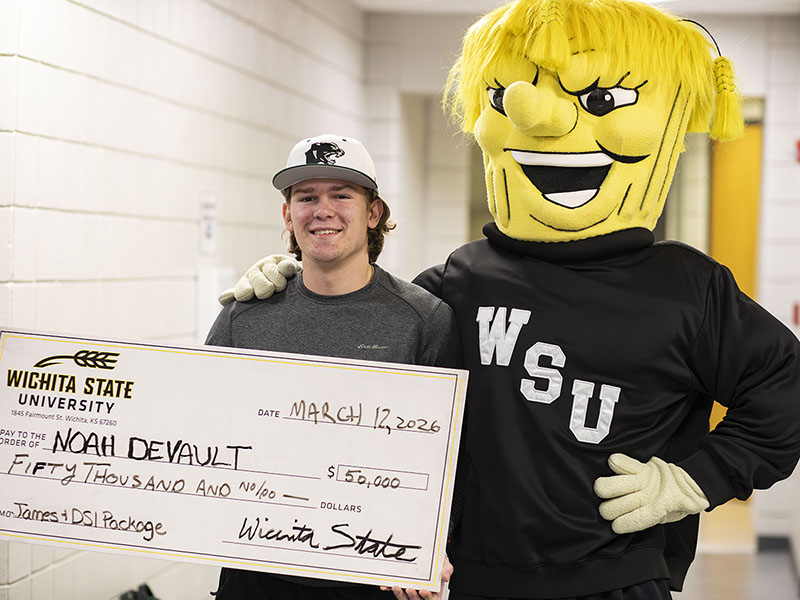 Noah DeVault stands next to WuShock and holds and oversized check for $50,000. 