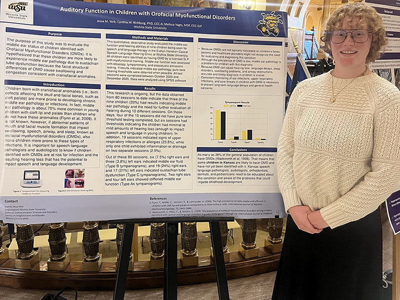 Jessica York poses in front of her research poster at the Kansas state capitol