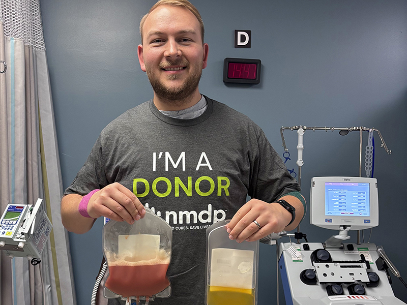 Joshua Geisler holds up two bags of fluid