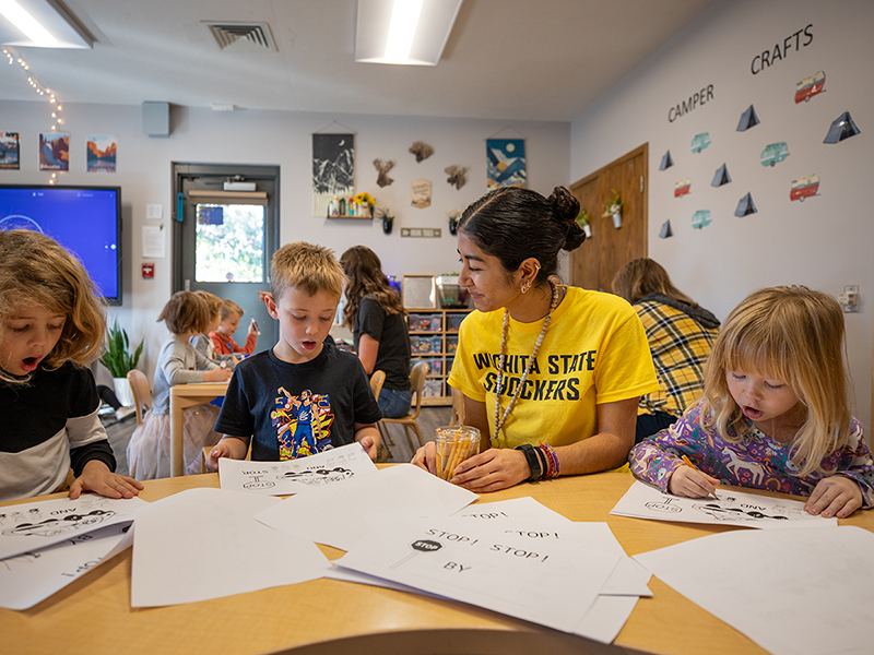 A teacher works with three students in a classroom setting. 