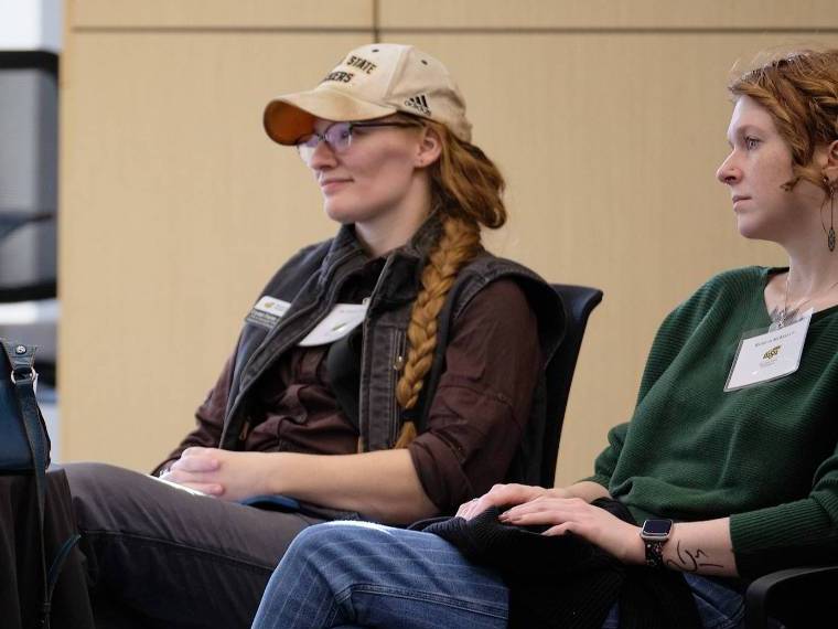 Two female professors watch a presentation.