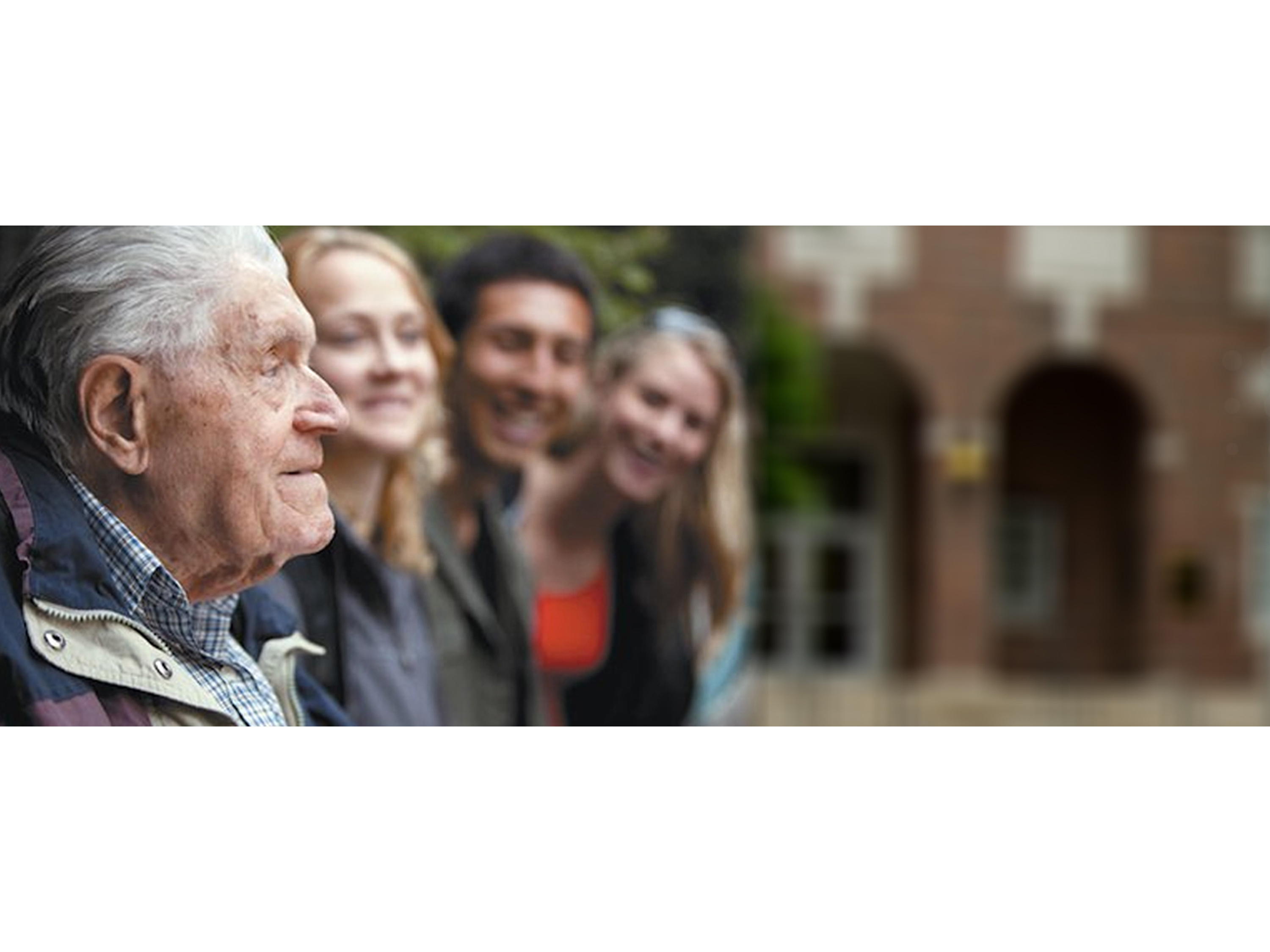 An elderly man looking to the right next to three other people.