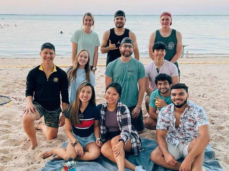 Students from the Pre-Physical Therapy Student Organization pose in the sand by a lake.
