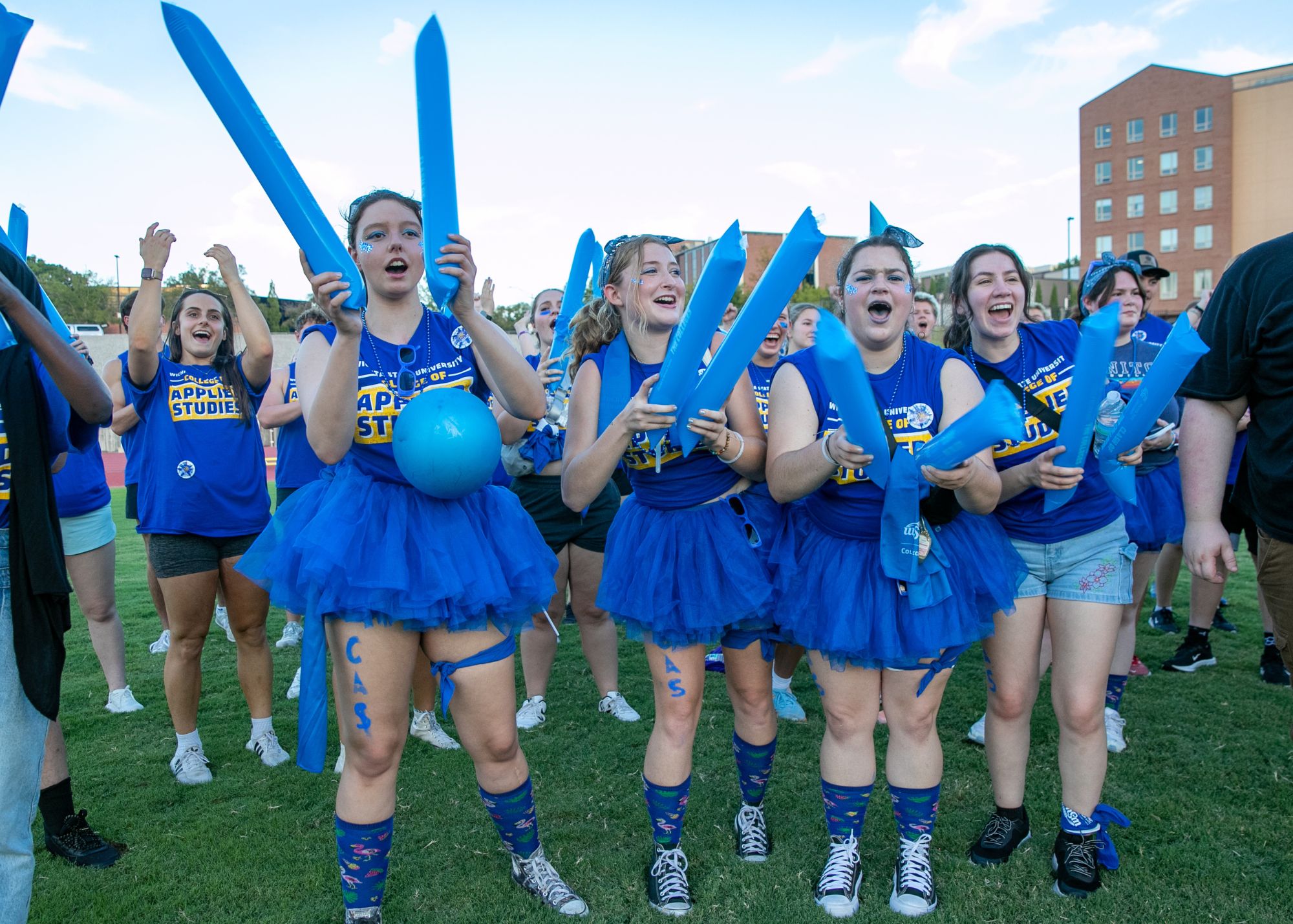 Clash of the colleges - students with swag gear cheering dressed in CAS blue tshirts