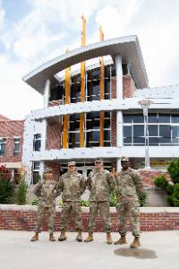 Four service members standing in front of Rhatigan Student Center. 