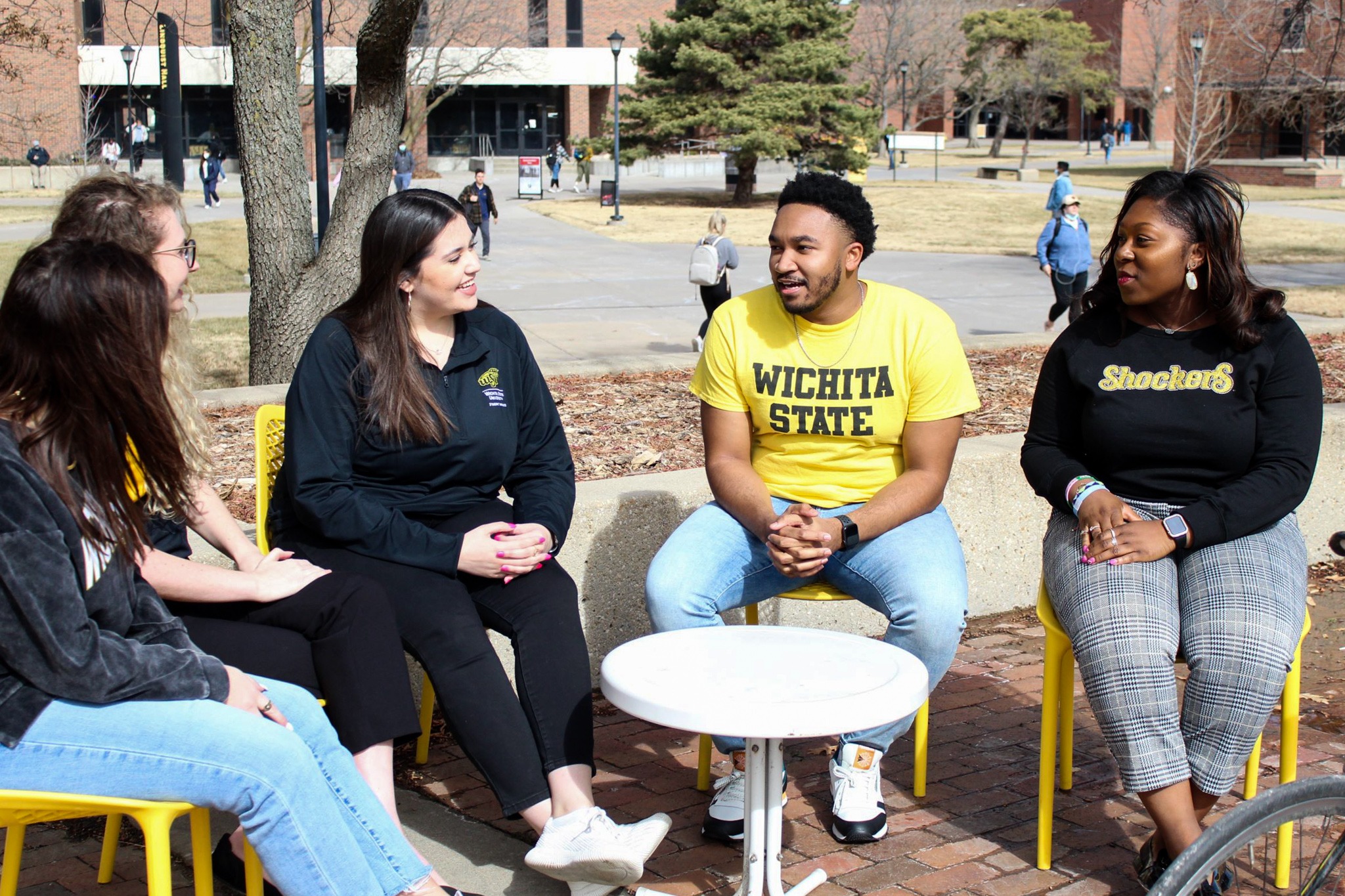 Higher Education Student Affairs students sit outdoors and talk to one another