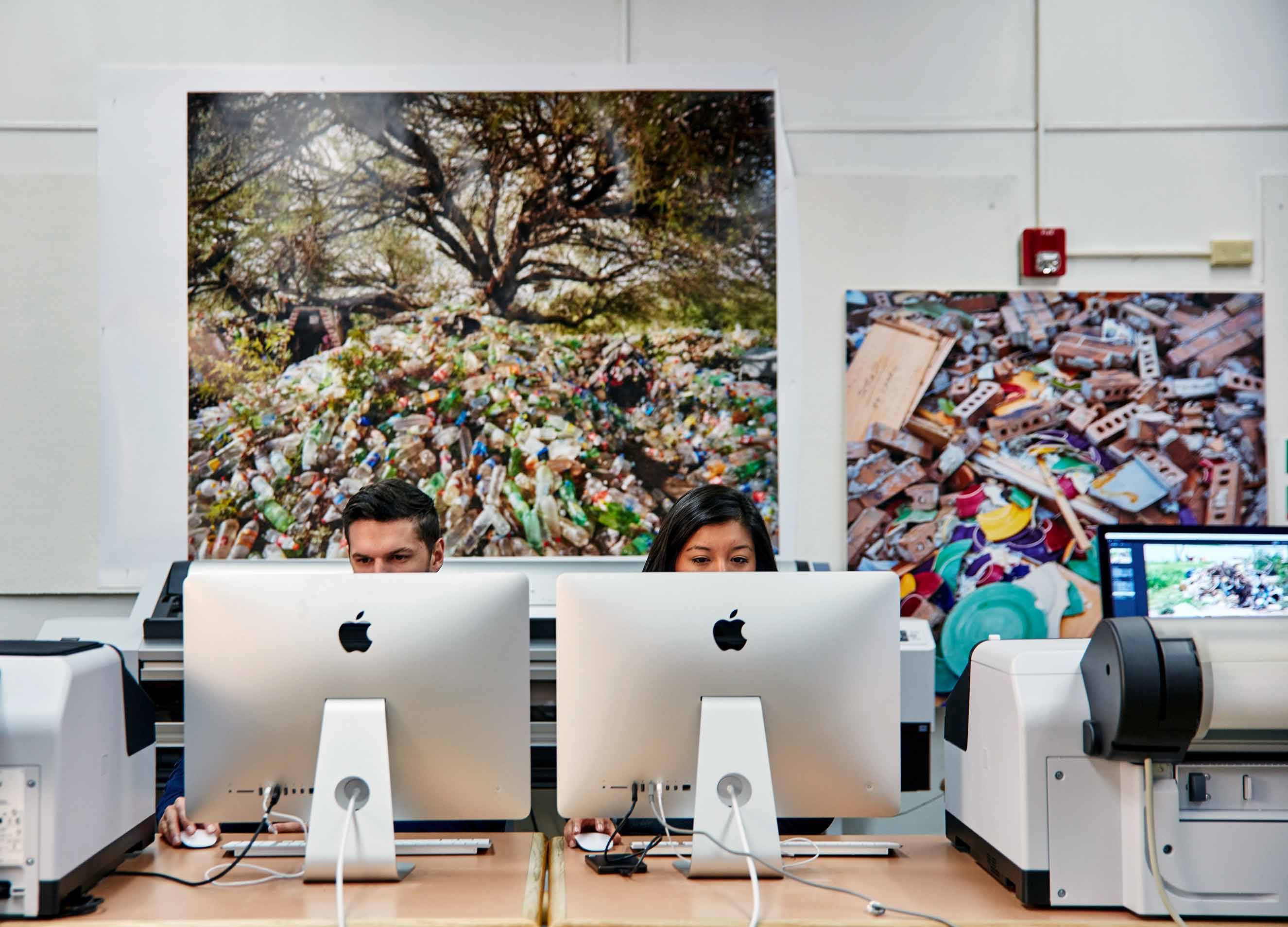 Two students working side-by side on two different computers. 