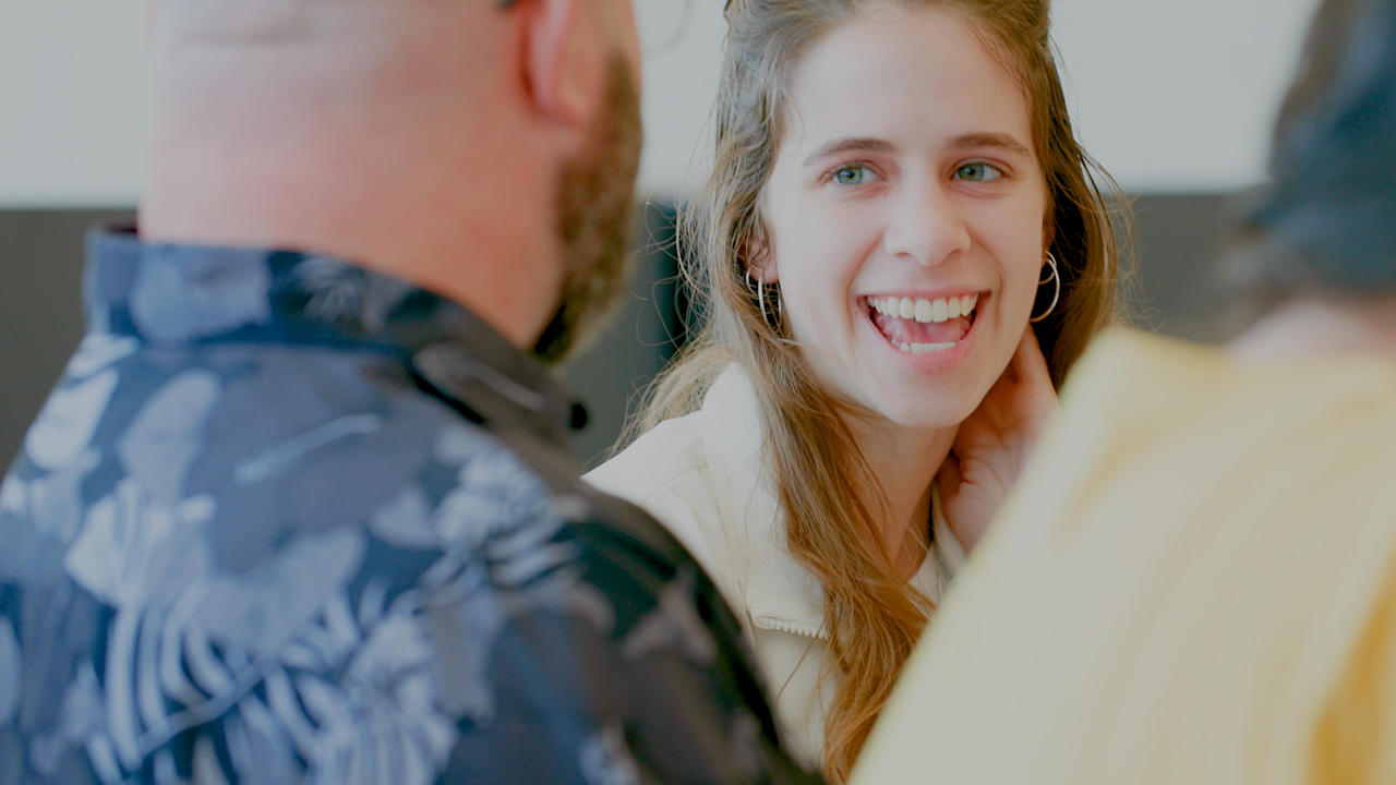 A student laughs while talking to two other students