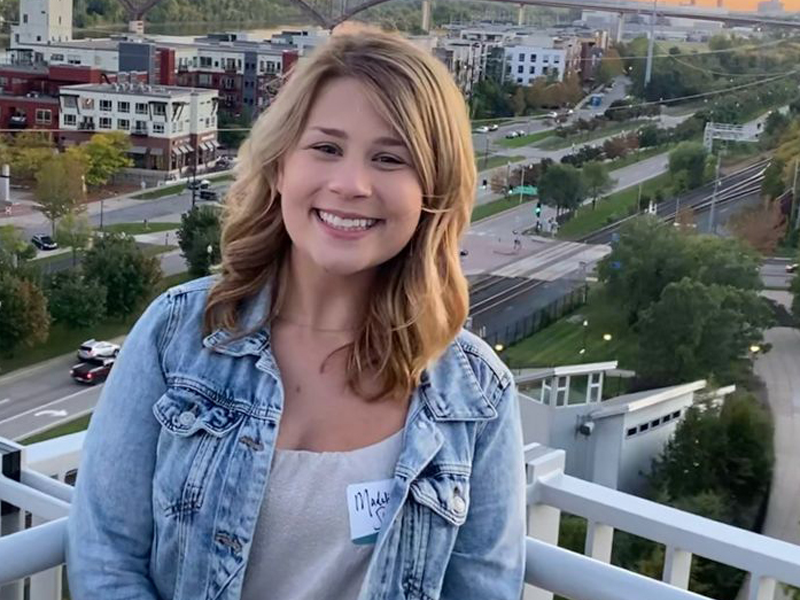 Madeline Shonka posed on a rooftop with city scape behind her.