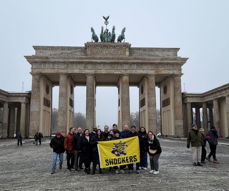 Wichita State students and faculty holding a shocker flag in front of the Brandenburg Gate