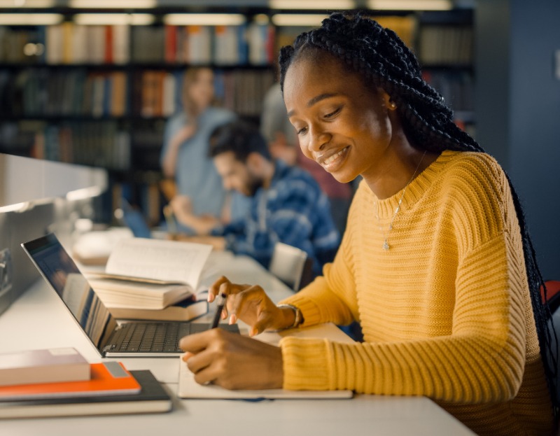 Two students working on computers and comparing information. 