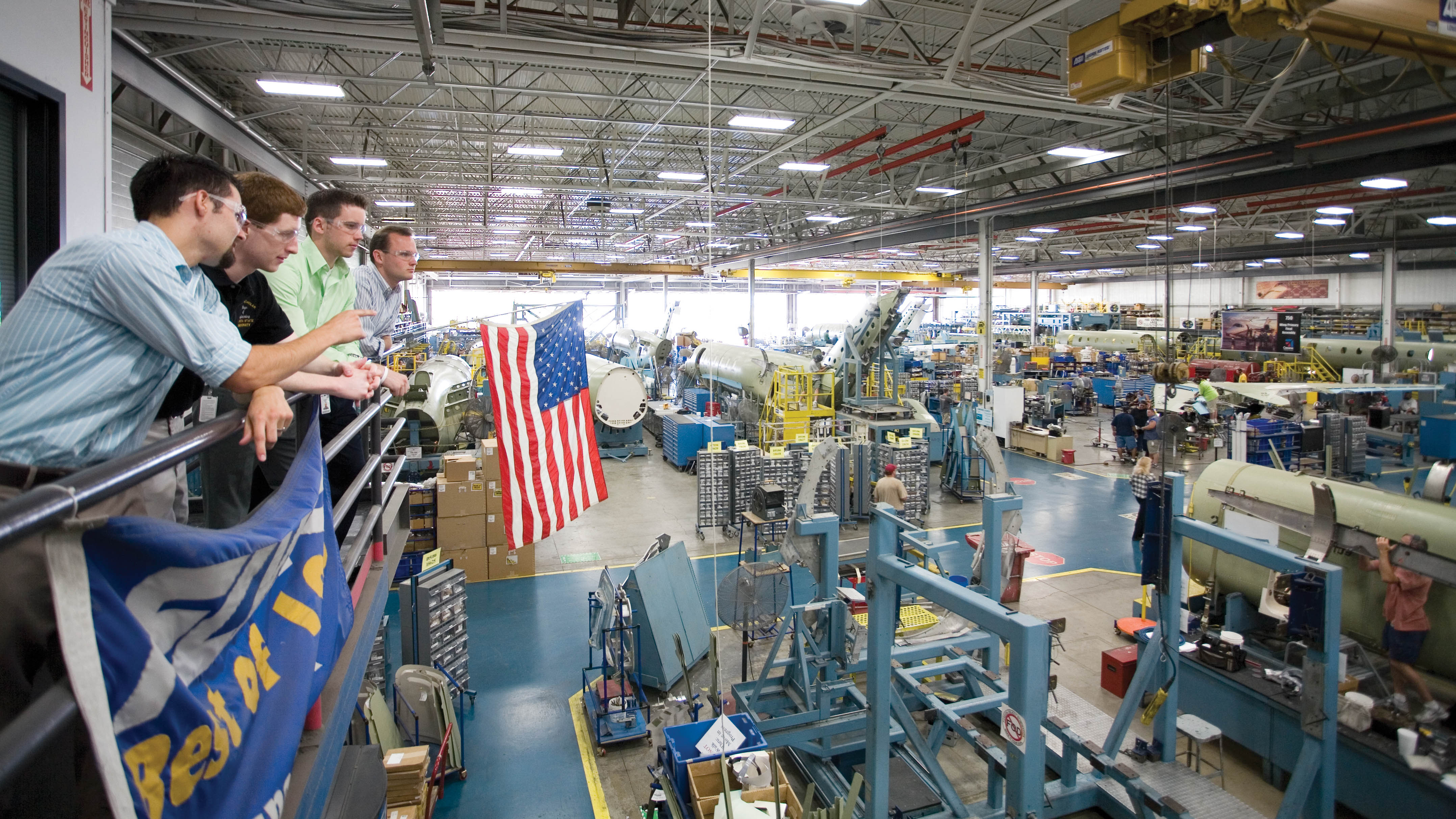 Four students look over an aerospace shop floor