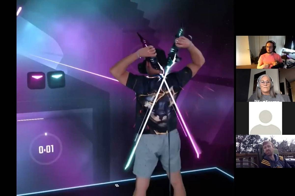Person wearing a VR headset and using controllers in a virtual reality game, with glowing swords crossed in front. A video call with three participants is shown on the side.