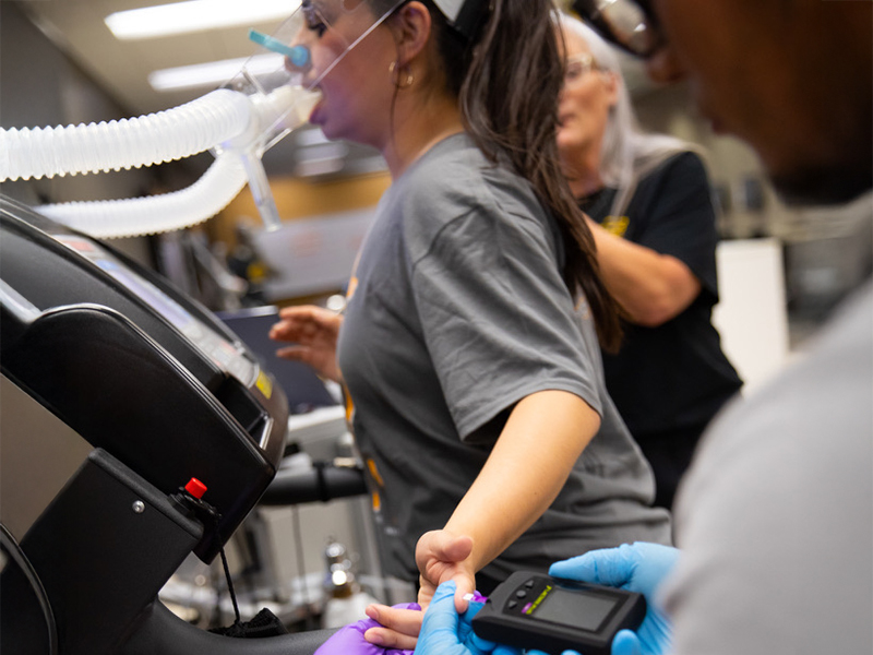Two students administer a blood lactate test in the human performance studies lab.