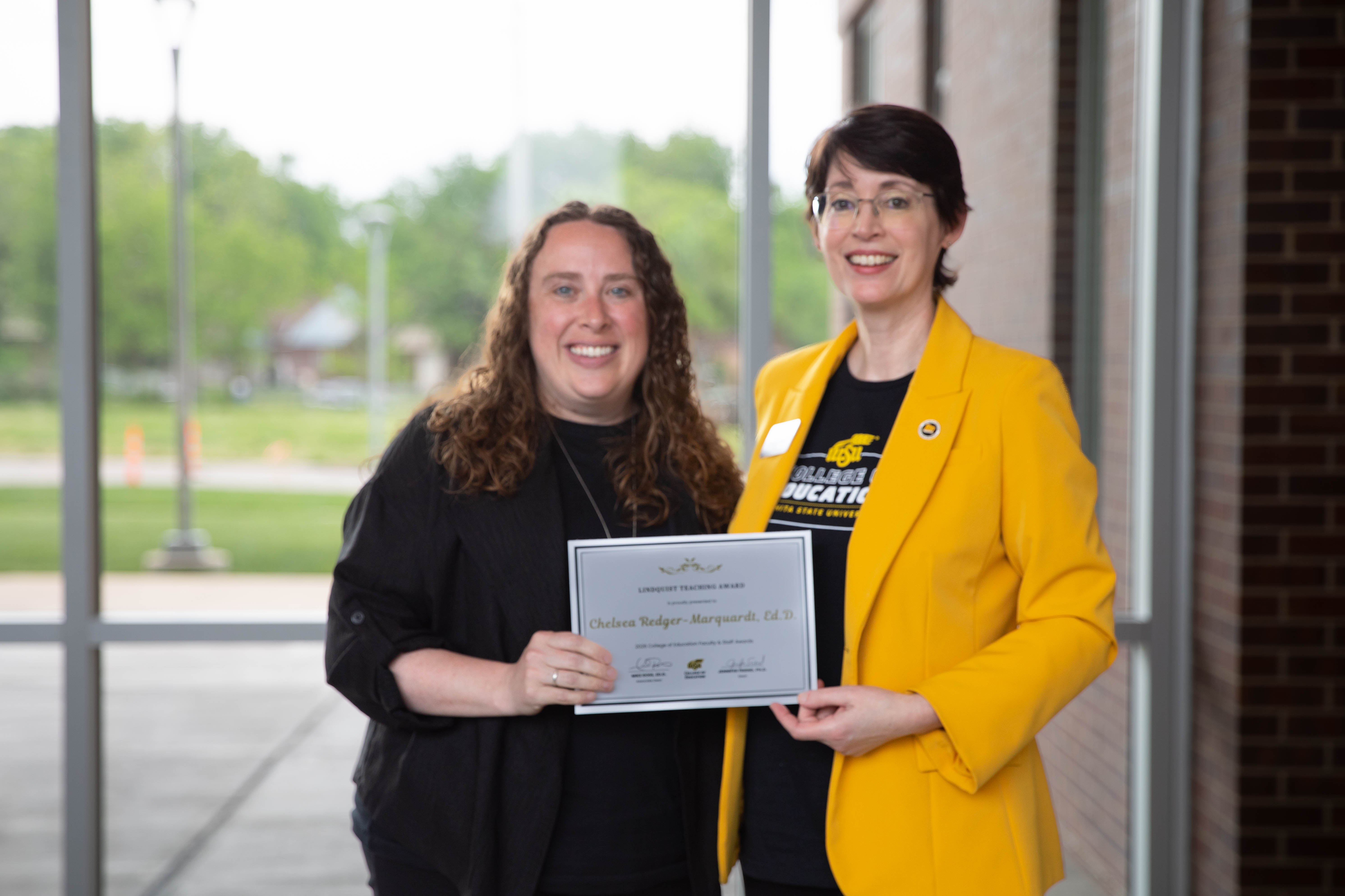 Dr. Chelsea Redger-Marquardt holds a Lindquist Teaching Award certificate while posing with Dr. Jennifer Friend, dean of the College of Education.
