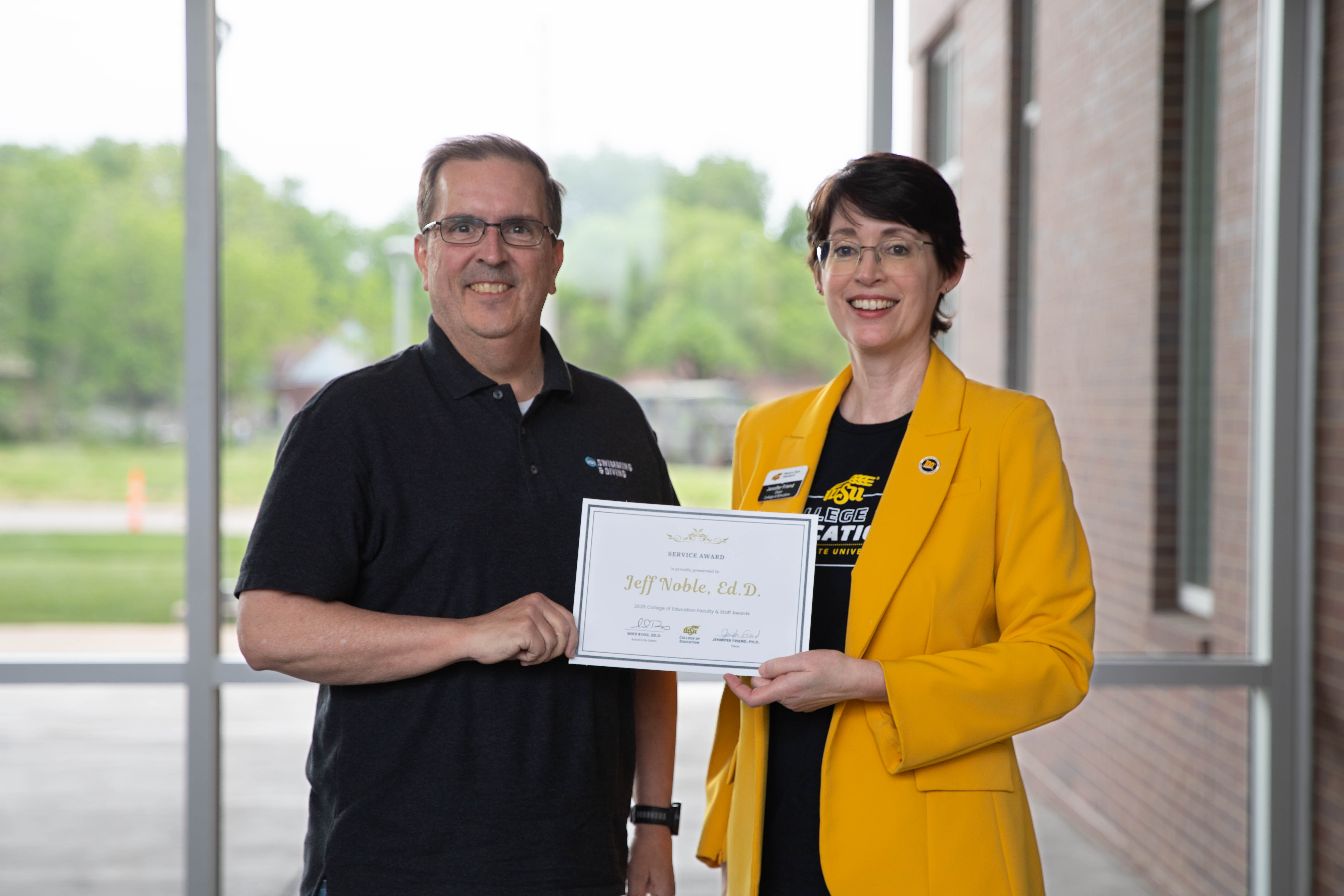 Dr. Jeff Noble holds a service award certificate while posing with Dr. Jennifer Friend, dean of the College of Education.